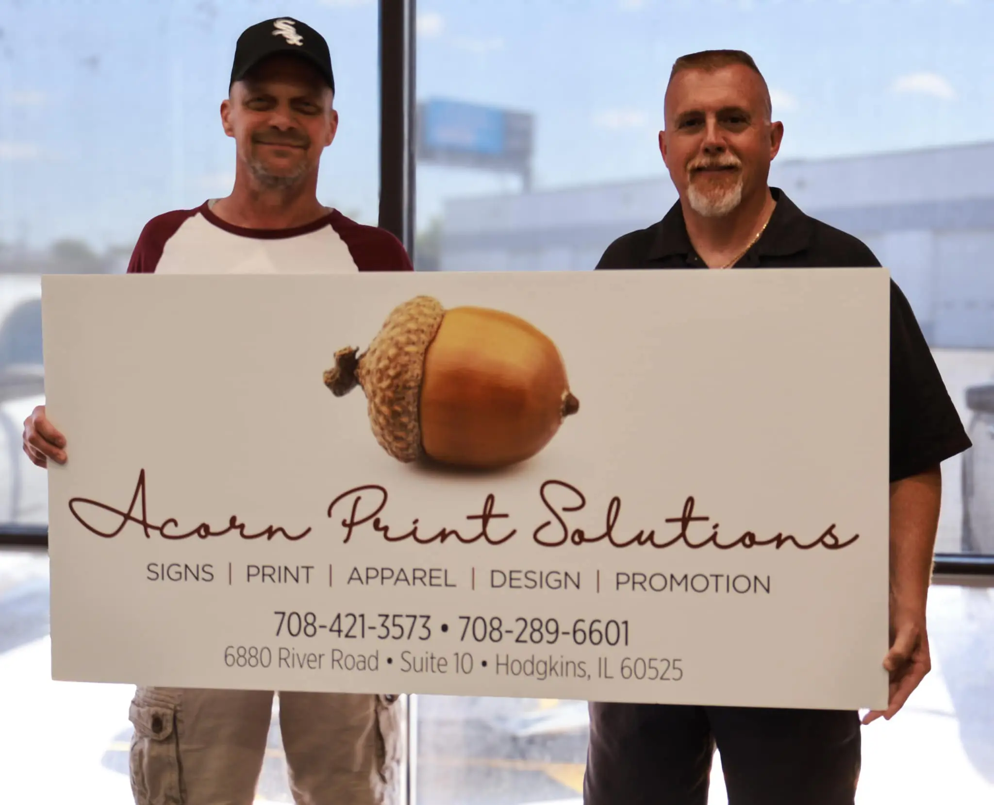67bcd65609e0a_Owners (1) Two men holding a sign that says acorn rent solutions.